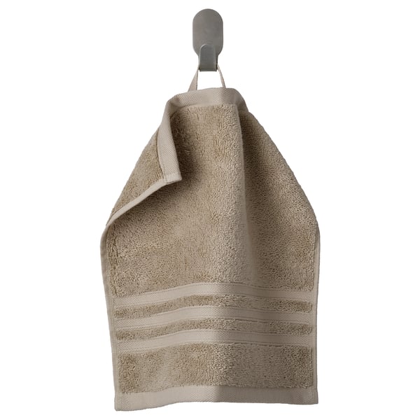 Beige BROKGLIM organic cotton towel with striped pattern hangs neatly on a wall hook. Soft, absorbent with a decorative border.