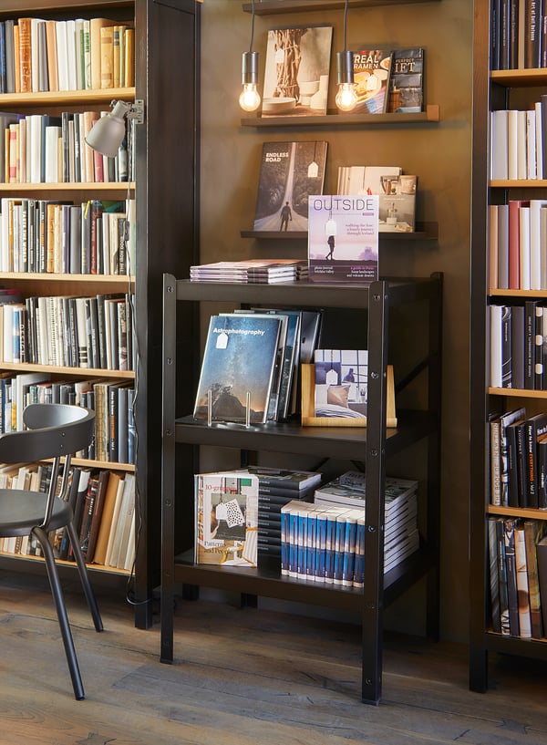 Library with bookshelves, lights, and books on central black metal shelf.