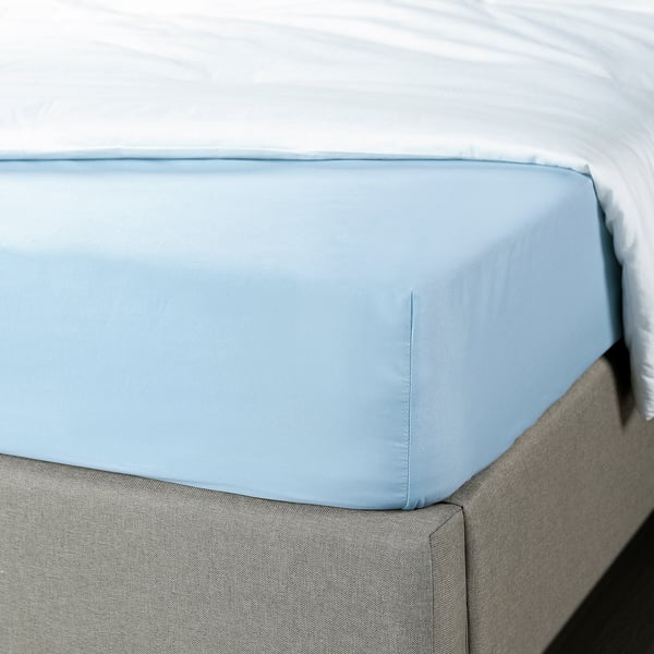 Blue fitted sheet on bed, made of soft, 100% recycled polyester, fits mattresses up to 16 cm thick.