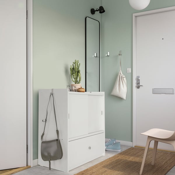 Modern entryway with BRUKSVARA storage, hooks, cactus, and blue rug.