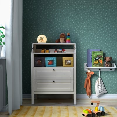 Childrens room with BRUMMIG lamp, toy shelf, and green wall decorations.
