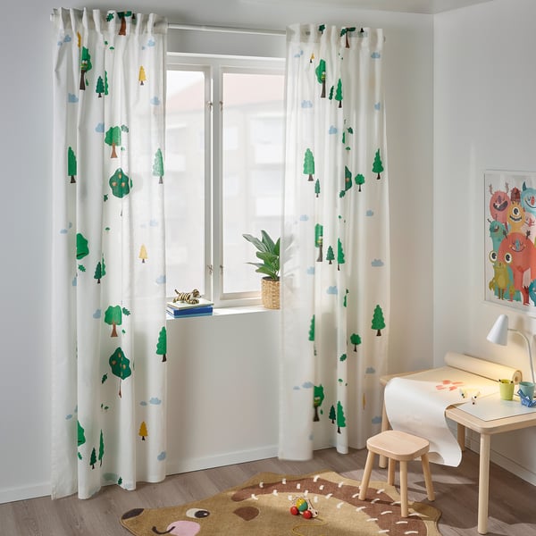 Kids room with BRUMMIG curtain, trees, plant, bear rug, table, & colourful art.