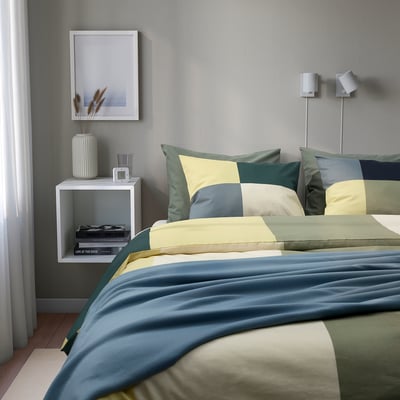 BRUNKRISSLA duvet on king bed with nightstands, muted colours.