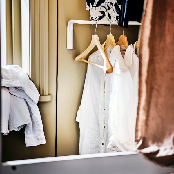 Clothes hangers in a closet. Wooden hangers hold shirts and jacket, preventing wrinkles and maintaining shape.