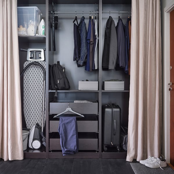 Closed closet with ironing board, clothes, and luggage. BUMERANG hangers visible; white iron, dark board.