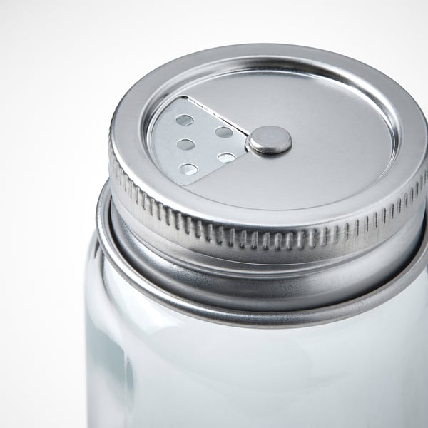Close-up of a clear glass jar with metal lid, featuring a spout and small openings, suggesting high-quality craftsmanship.