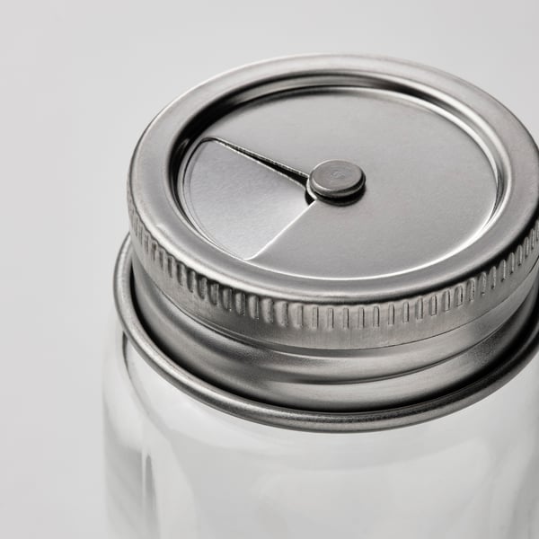 Clear glass jar with metallic lid, featuring a small spout and knurled edge for grip, reflecting quality and practicality.
