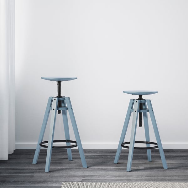 Two blue adjustable bar stools, height 90-110 cm, against a white wall.