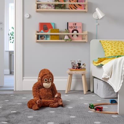 Kids room with large DJUNGELSKOG ape toy, bookshelves, stool with stuffed animals, crib, and toy train.