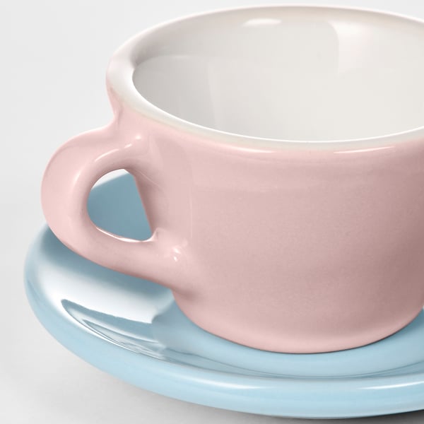 Close-up of pink kids mug on light blue saucer, both smooth and well-made.