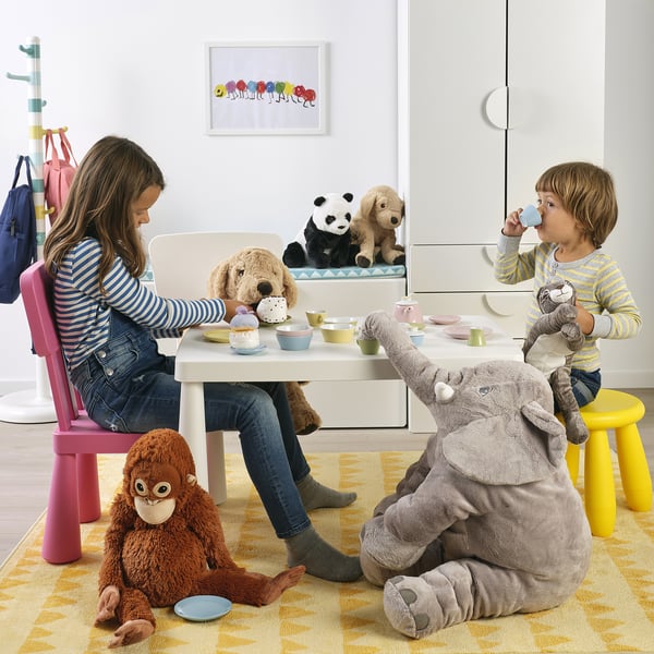 Kids enjoy a tea party with stuffed animals, using a child-sized table and colourful cups and saucers.