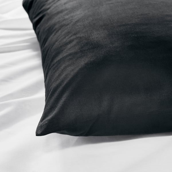 Dark pillow on white sheets, illustrating soft, high-quality fabric close-up.