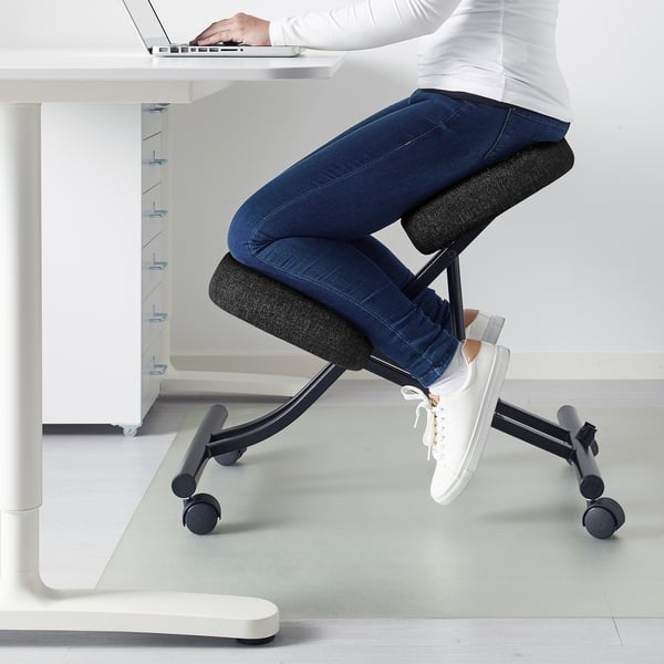 Using kneeling chair at desk, promoting better posture.