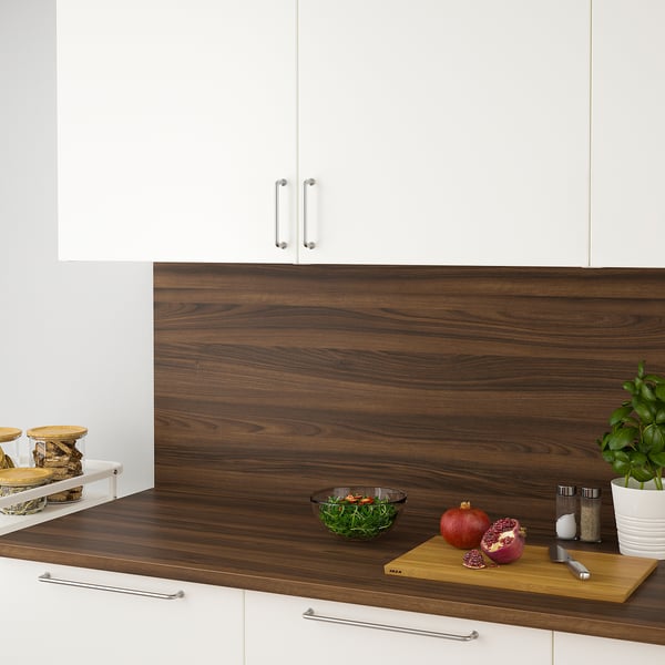 Modern kitchen counter with wooden surface, white drawers, and handles. Bowls, fruits, and herbs for meal prep.