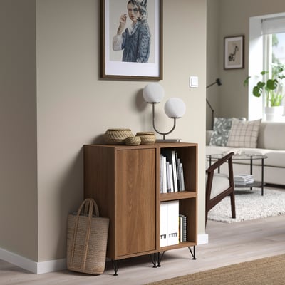 Mid-century modern wooden cabinet, dark brown, hairpin legs. Fits between wall and chair, holds books, with woven baskets.