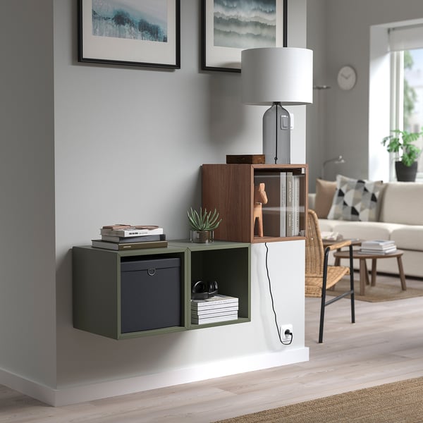 Modern living room with EKET wall-mounted storage; holds books, lamp, & decor. White & wooden finish. Positioned below two framed wave prints.