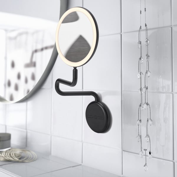 Black wall-mounted mirror with built-in light and magnification, ideal for makeup or shaving.