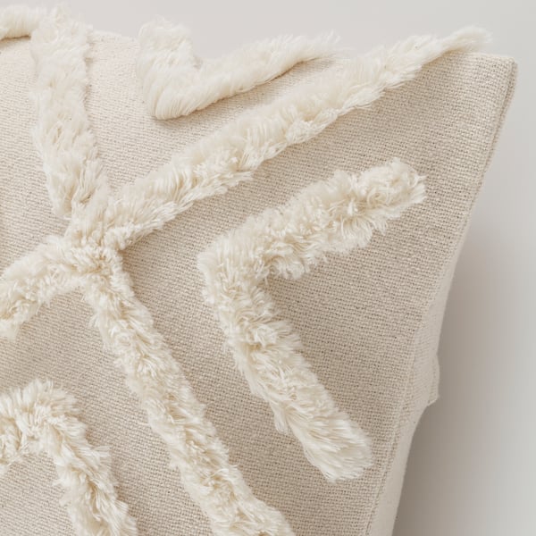 White cushion cover with textured, looped geometric design. Soft cotton with a hidden zip for easy cleaning. Boho-style decor.