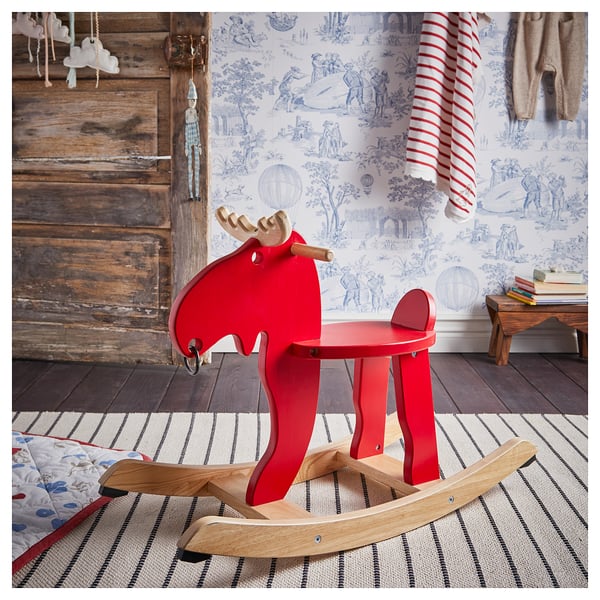 Bright red rocking horse toy with wooden details sits on striped rug. Perfect kids play item with rustic decor.