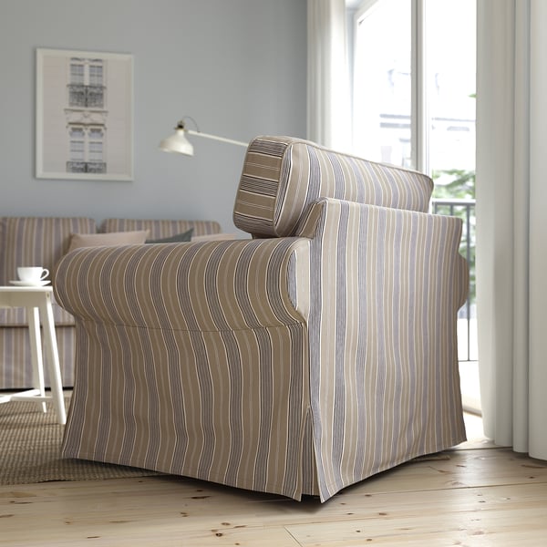 A striped armchair by a window with a large backsplash cushion offering back support.