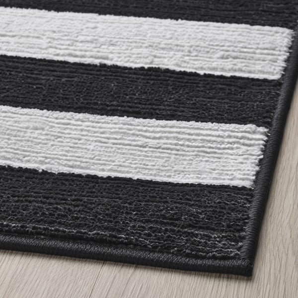 Black and white striped rug with a textured surface, laid on wooden floor; appears soft and high-quality.
