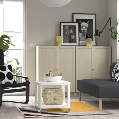 Modern living room with wooden cabinet, vibrant rug, and polka dot chair.
