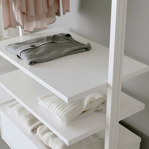 White shelf system with movable and adjustable shelves holding folded clothes.