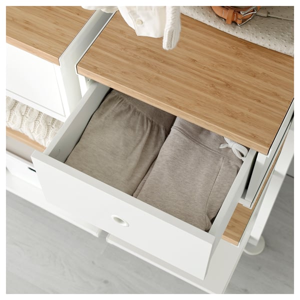Open drawer of a white and bamboo ELVARLI unit revealing neatly folded pants, demonstrating its storage function.