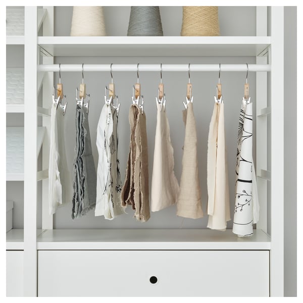 Open storage closet with wooden hangers holding fabrics, shown in white with gray background.