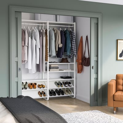 ELVARLI wardrobe in bedroom with shelves, hanging section, and orange chair.