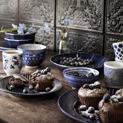 Blue & white tableware with berries, muffins, coffee, & metal art.