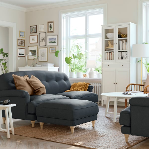 Well-decorated living room with a grey ESSEBODA sofa and footstool on a patterned rug.