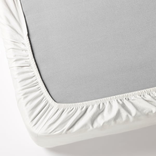 Close-up of fitted sheet covering mattress. Elastic edges ensure secure fit.