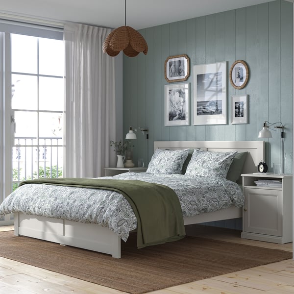 Traditional FÅGELFJÄLLET bed with ornate headboard, off-white, blue panels, wicker lamp, nature prints.