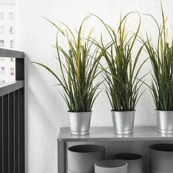 Three potted artificial plants on a shelf, realistic and low-maintenance, suitable for both indoor and outdoor use.