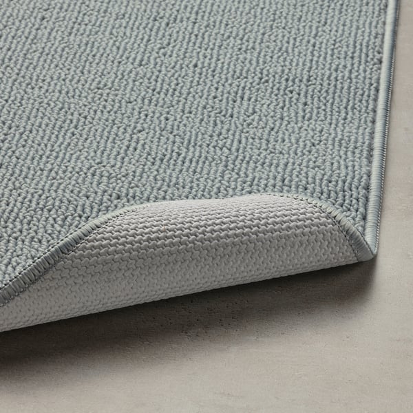 A rolled-up grey bath mat with a textured surface and latex backing, designed for quick drying and non-slip use.