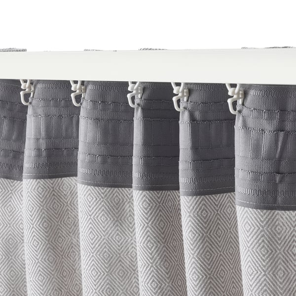 Grey curtains with geometric patterns hang on white clips, providing privacy and reducing glares.