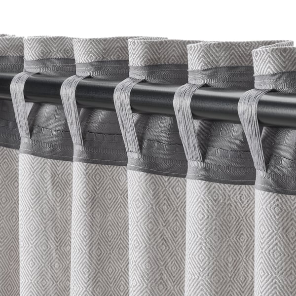 Grey patterned curtains with hooks hang from black rod, providing privacy and light reduction.