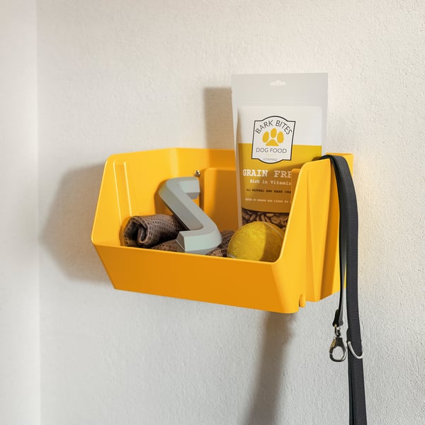 Bright yellow wall-mounted organiser holds dog food, leash, and toy. Part of a practical storage solution for pet supplies.