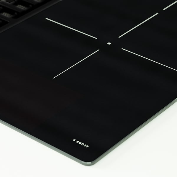 Black induction cooktop with four burners and touch controls. Brand name boost visible in corner.