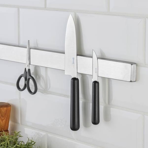 Three kitchen knives and scissors on wall magnet.