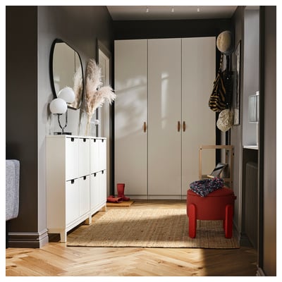 Neat entryway with white cabinets, mirror, red stool, jute rug, and boots.