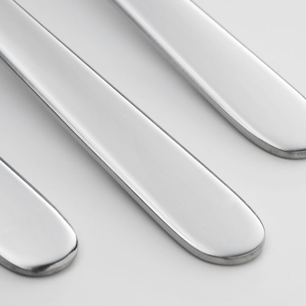 Four shiny, polished forks lie side by side, showcasing their sleek, smooth design.