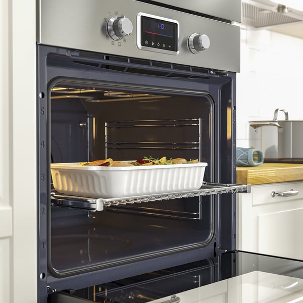 Oven with cooked vegetables, digital display, kitchen sink.