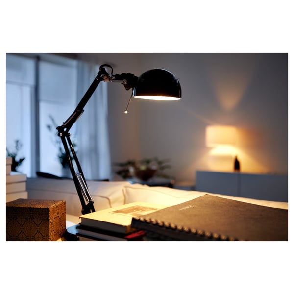 Black adjustable desk lamp illuminates an open book, highlighting its functionality for reading.