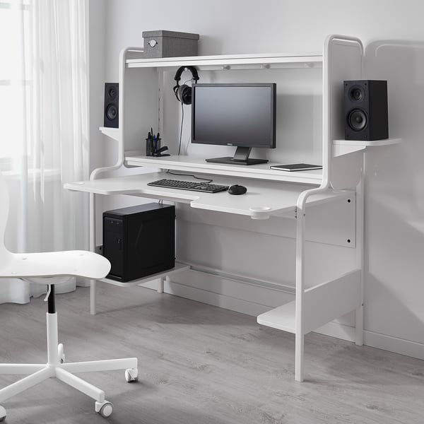 Modern white gaming desk with contoured top, integrated cup holders, and cable management, supporting a monitor, keyboard, and speakers.