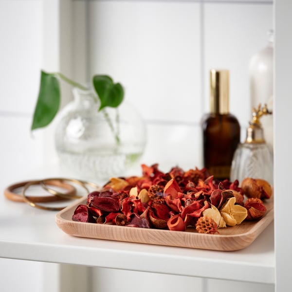 Wooden tray with red potpourri, rings, and decorative bottles. It provides organisation and adds a decorative touch.