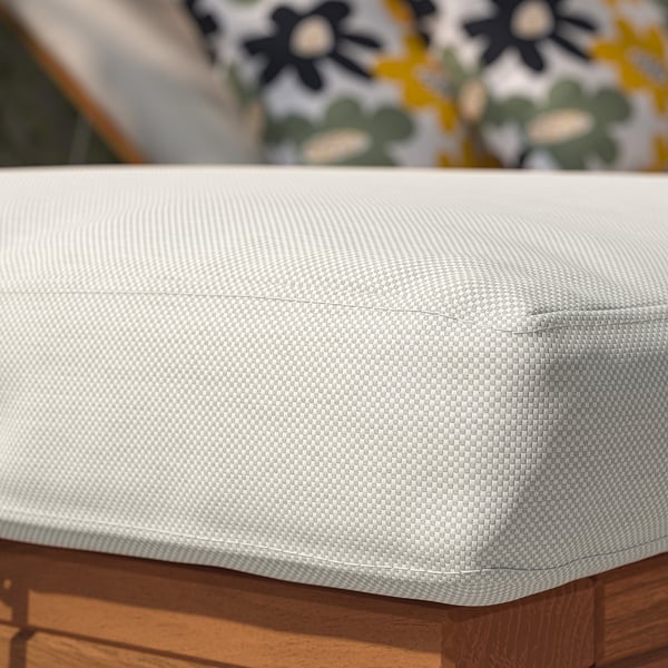 Close-up of outdoor cushion on wood, white chequered fabric, showing quality material and stitching.