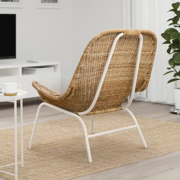 FRYKSÅS wicker armchair with white frame, beige seat, & back on textured rug in minimalist space.