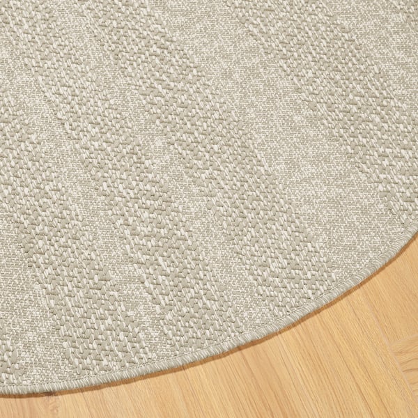 Round rug with textured beige pattern on hardwood floor, showcasing its intricate weave and smooth edges.